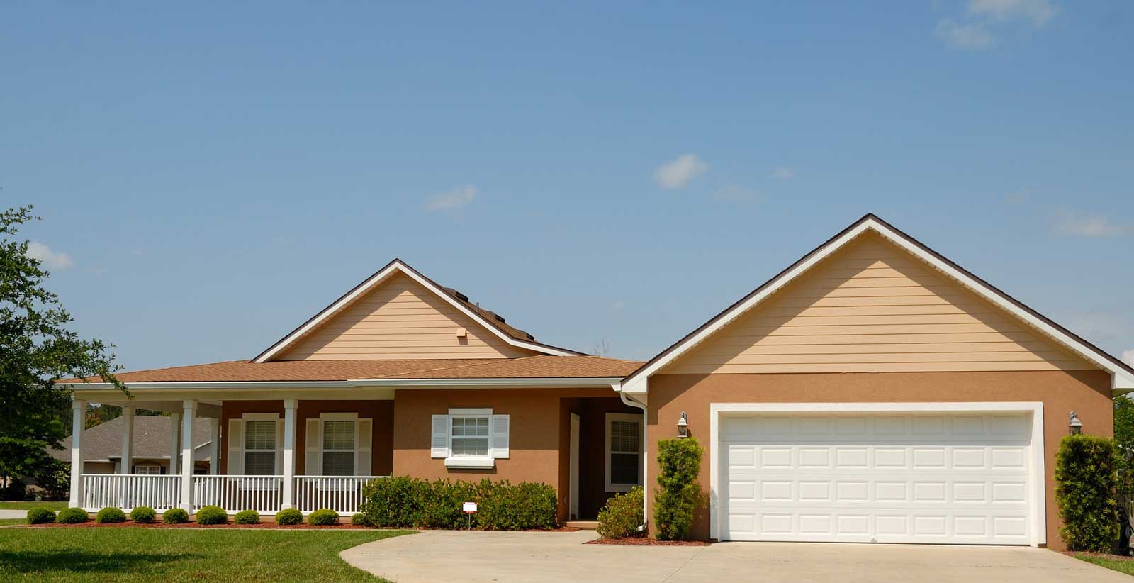 A tan house with a brown shingle roof