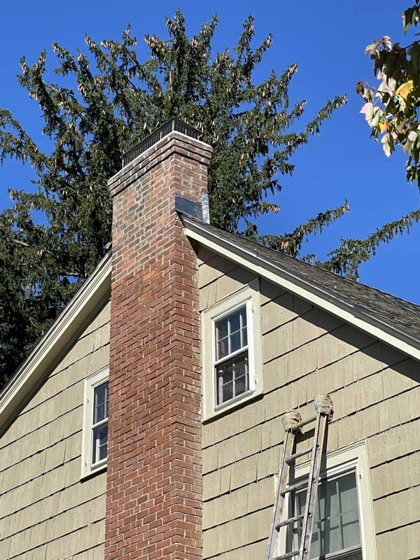 Side of tan house with a brick chimney